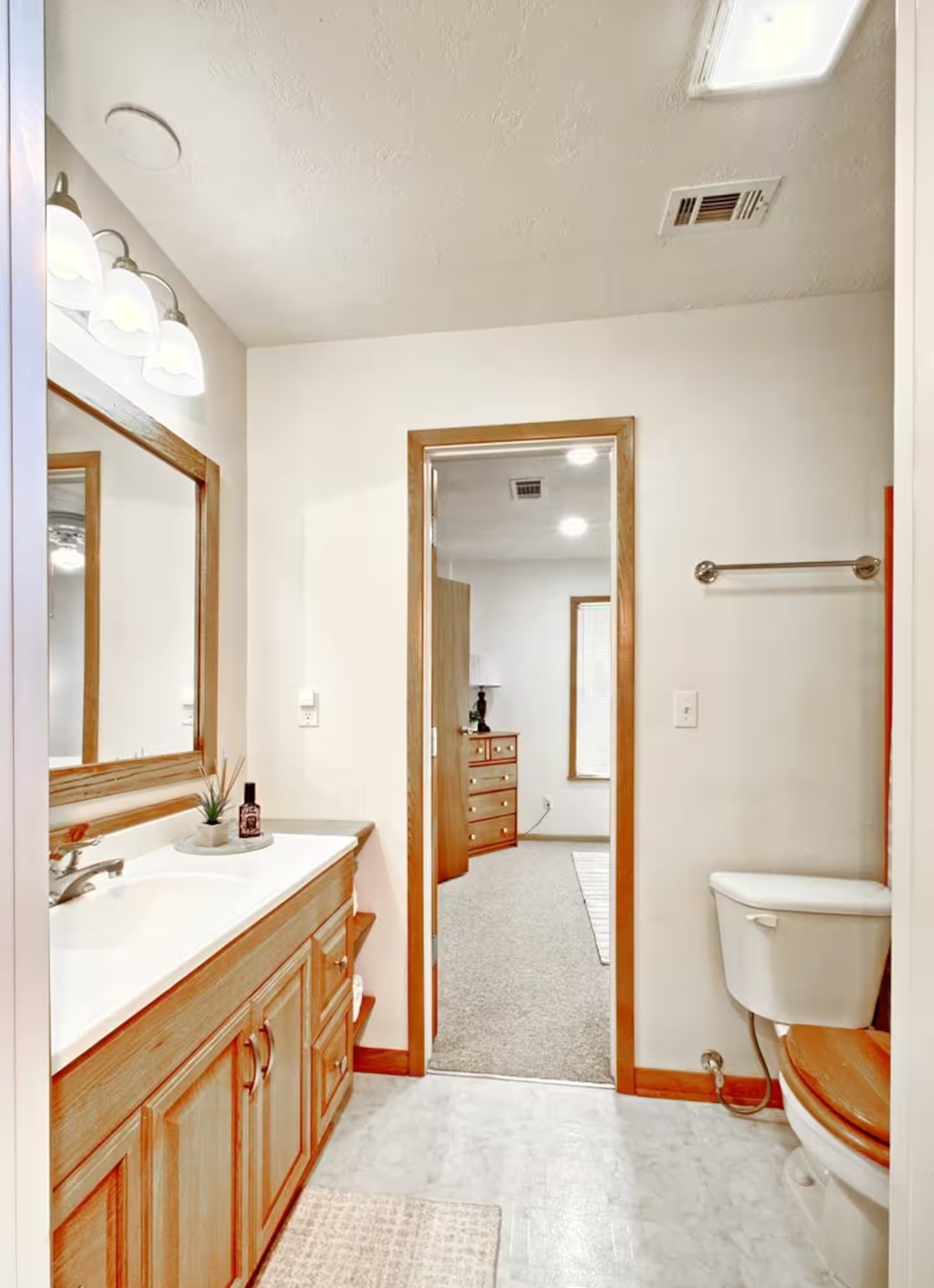 Jack and jill bathroom with wood vanity and pass-through to bedroom